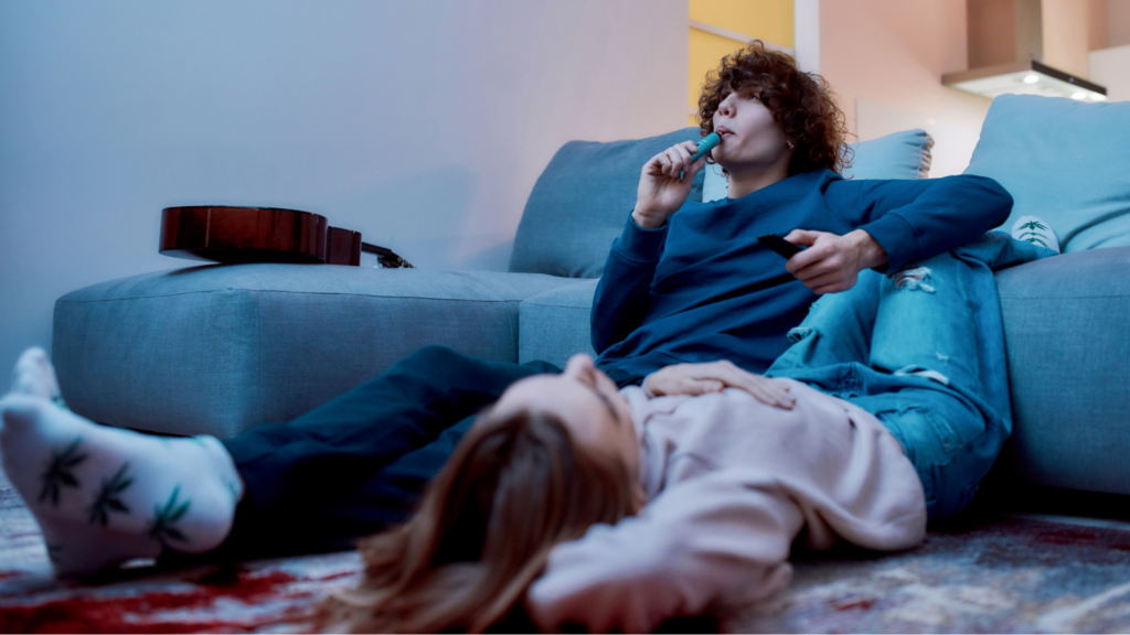 Young creative guy smoking marijuana from a vape pen or vaporizer while relaxing