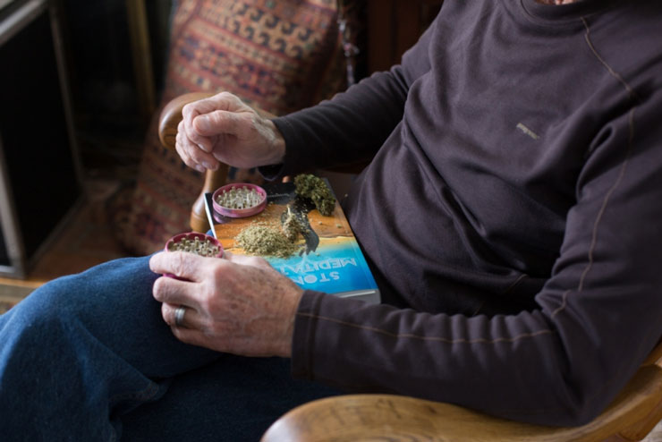 older man putting marijuana in a grinder