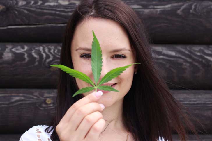 A woman holds a cannabis leaf