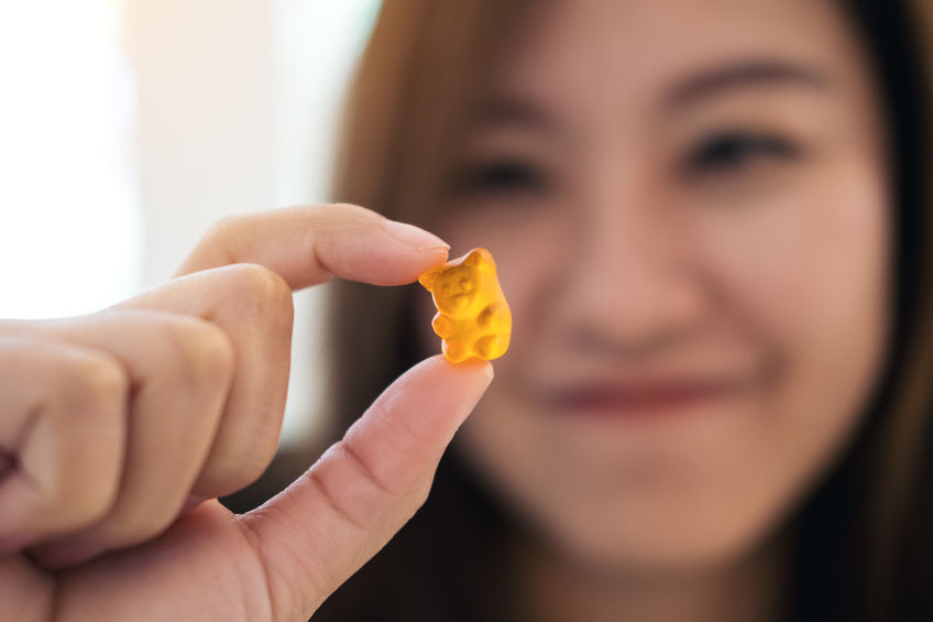 A woman holds up a cannabis gummy