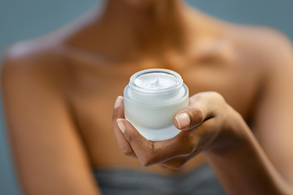 A woman holds a jar of CBD cream