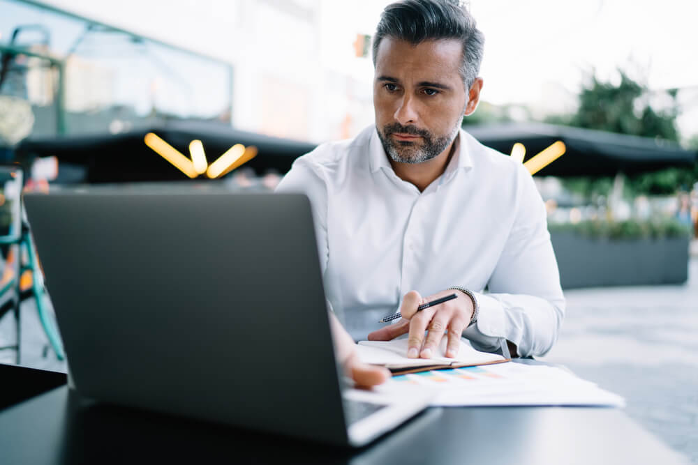 An adult man concentrates while working at his laptop