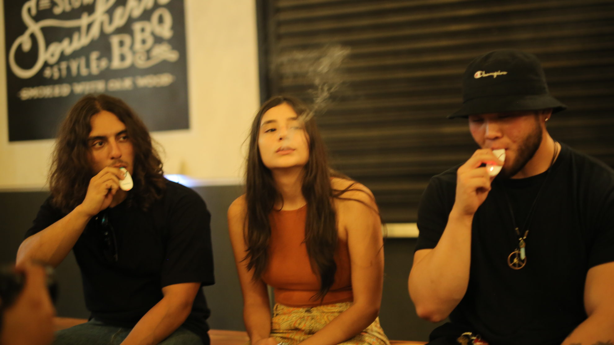 Three friends use their Basiq vaporizers outside a club